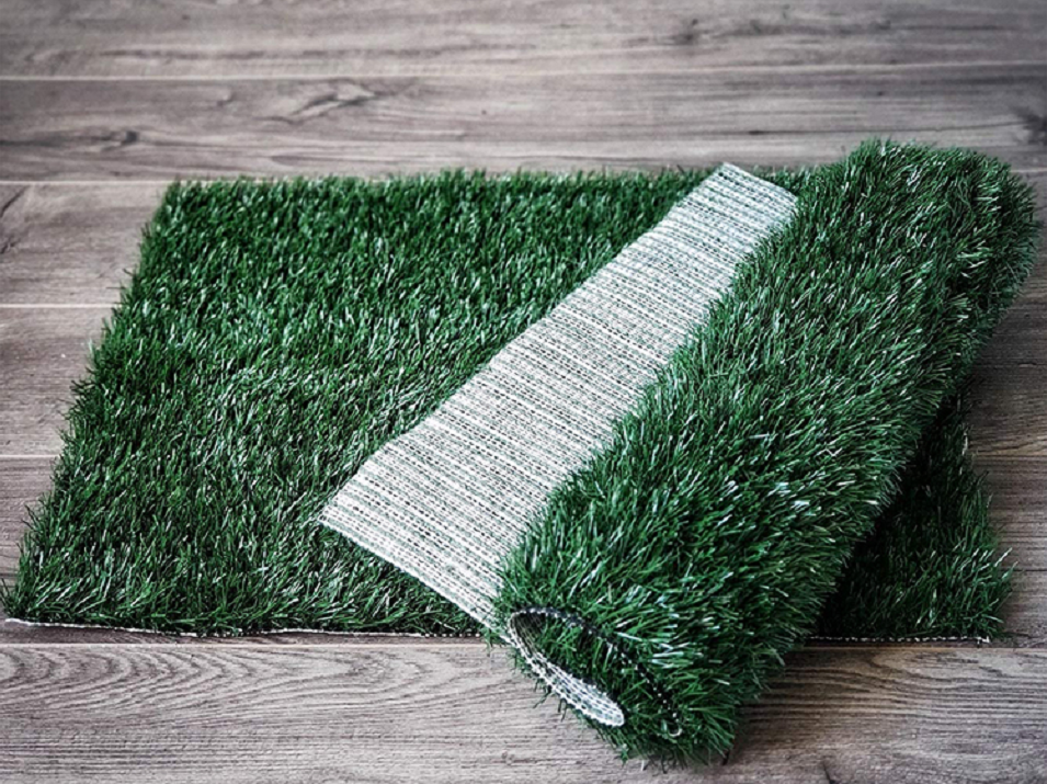 Roll of artificial grass on a wooden floor at Pet Servo