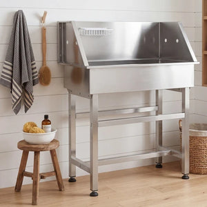 Stainless steel kitchen prep table with wooden stool and cleaning supplies against a white tiled wall at Pet Servo