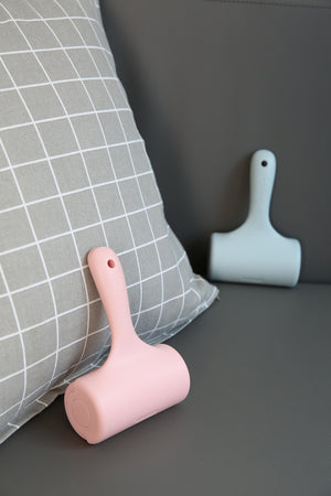 Pink and light blue pet grooming tools on a dark surface with a gray pillow in the background at Pet Servo