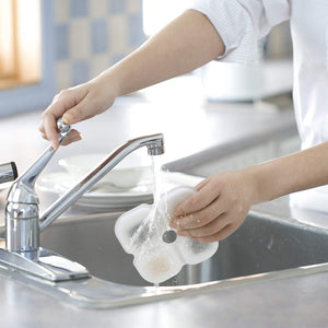 Person washing dishes in a kitchen sink with running water at Pet Servo