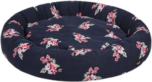 A round, tufted pet bed in navy blue fabric with a pink and green floral pattern, shown against a plain white background at Pet Servo