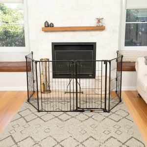 Black metal pet gate in a living room with a fireplace and white couch.