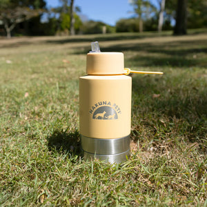 Beige water bottle with a logo on grass
