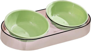 A double pet bowl set featuring two light green ceramic bowls nested inside a metallic rose gold base, shown on a plain white background at Pet Servo