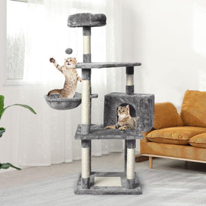 Cat playing with a ball on a multi-level cat tree in a living room at Pet Servo