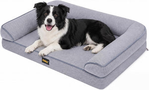 A black and white Border Collie dog lies on a gray raised pet bed with armrests, photographed on a clean white background. A small PurrX brand label is visible on the front edge of the bed at Pet Servo