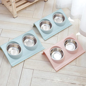 Three pet bowls on elevated stands in pastel colors on a light wooden floor at Pet Servo