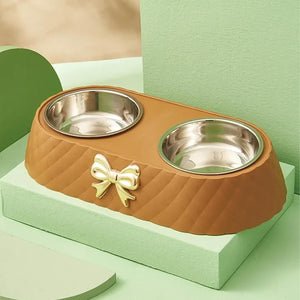 Brown pet bowl with two silver bowls and a gold bow on a green platform at Pet Servo