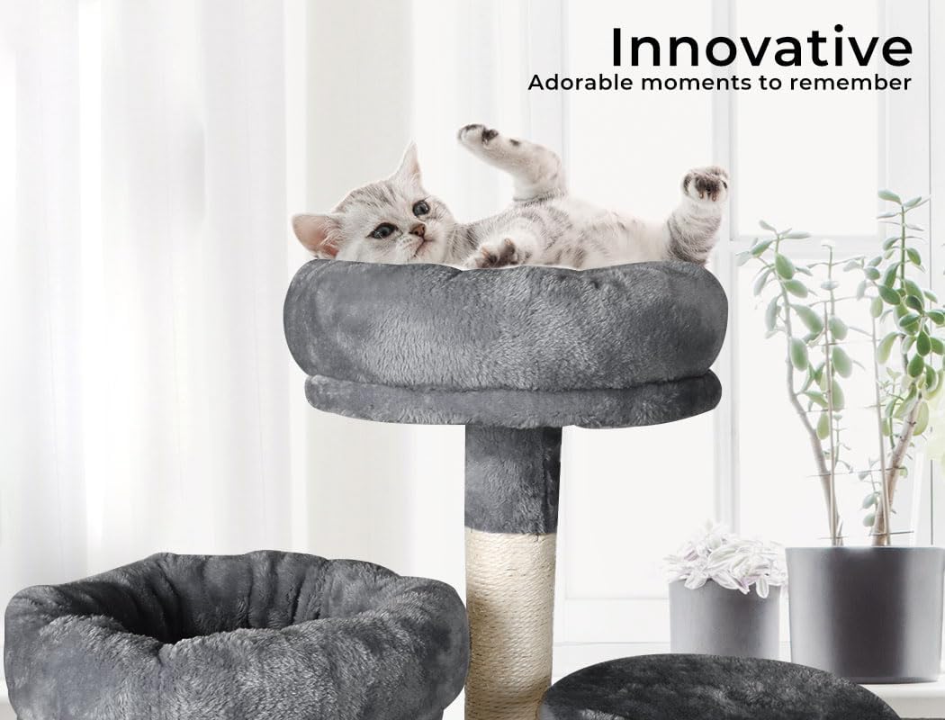 A gray plush cat tree with a cat lying on the top platform in a bright room. The tree includes a scratching post wrapped in natural sisal and a separate round gray cat bed in the foreground at Pet Servo