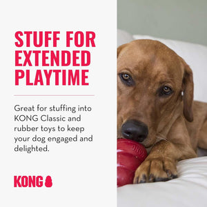 A brown dog lying on a white surface while chewing a red Kong toy. The left side has promotional text reading 'STUFF FOR EXTENDED PLAYTIME' and 'Great for stuffing into KONG Classic and rubber toys to keep your dog engaged and delighted at Pet Servo