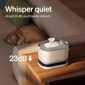 Pet water fountain on a wooden table with a cat sleeping in the background, emphasizing whisper quiet operation.
