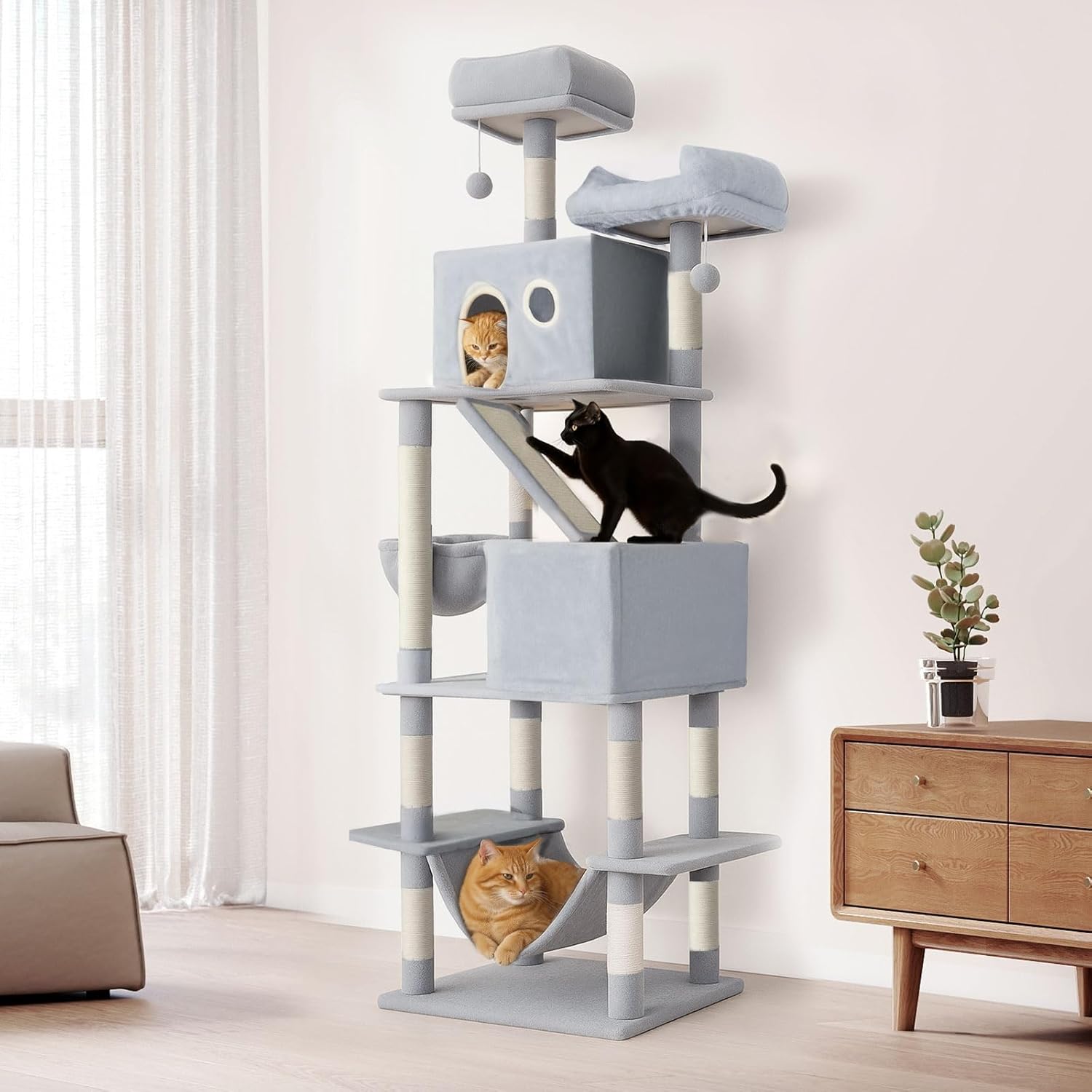 A tall gray and cream cat tree with multiple levels, platforms, a scratching post, and two cat beds, shown in a bright room with two cats on and inside the tree at Pet Servo