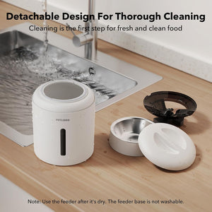 White pet feeder with detachable parts on a kitchen counter next to a sink.