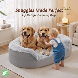 A round gray inflatable pet bed with a fluffy light gray lining and a plush faux-fur trim, shown in a bright living room with two golden retriever dogs sitting inside and a toddler in blue overalls standing beside it. Text at the top reads 'Snuggles Made Perfect' and 'Soft Beds for Dreaming Dogs.
