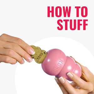 A pink KONG dog toy is being inserted with a dog treat, held by two hands against a white background with bold pink text reading 'HOW TO STUFF' at the top at Pet Servo