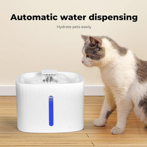 A white automatic pet water dispenser with a blue vertical indicator light stands on a wooden floor next to a white and gray cat. Text at the top reads 'Automatic water dispensing' and 'Hydrate pets easily' at Pet Servo
