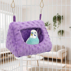 Purple bird nest with a blue and white parakeet inside, hanging from a cage at Pet Servo