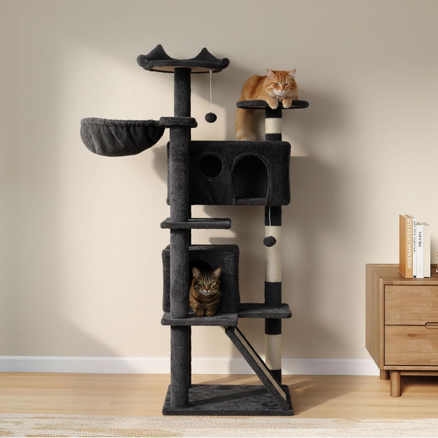 A tall dark gray cat tree with multiple platforms, a hanging bed, and two cats resting and playing on it, set in a room with a beige wall and light wood floor at Pet Servo