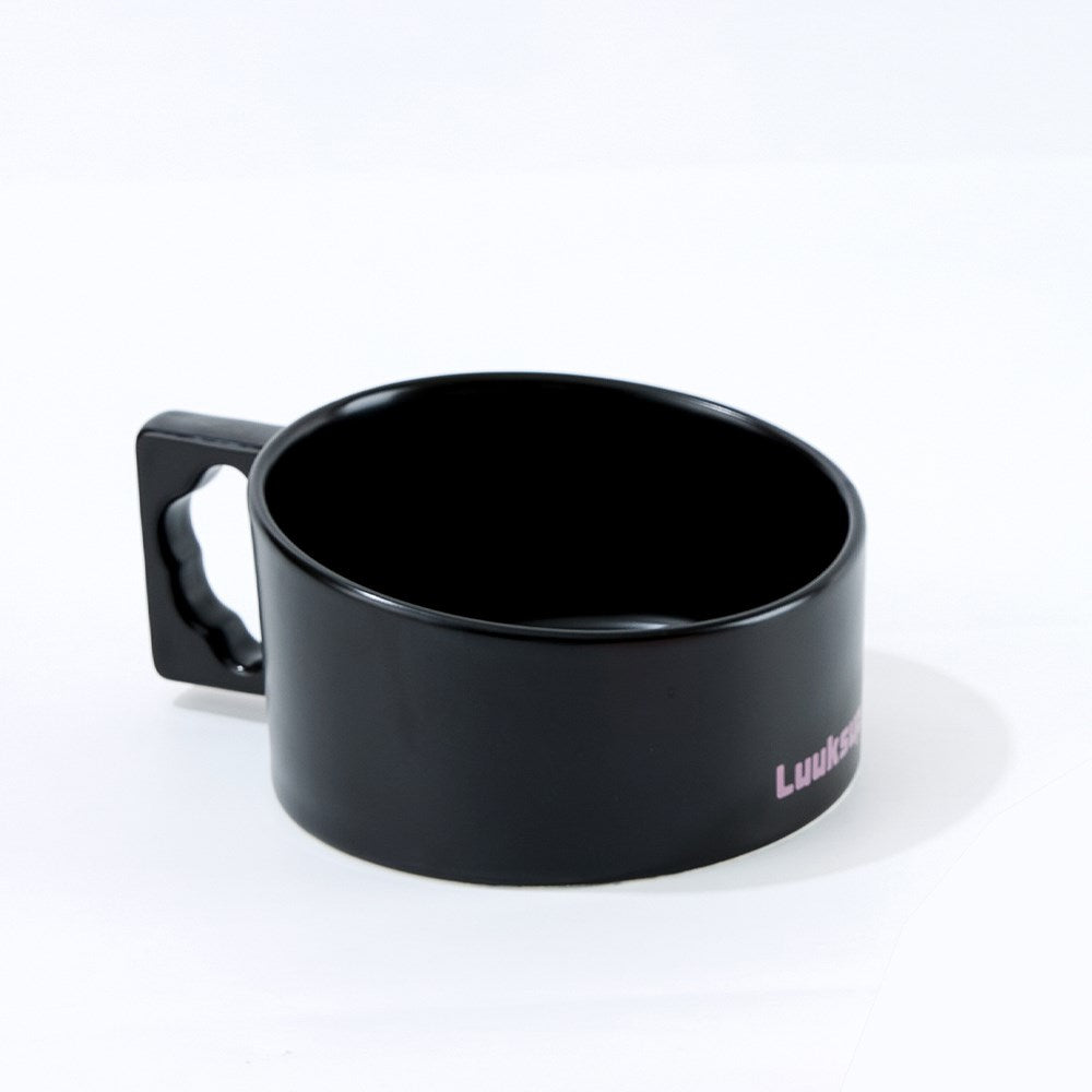 A glossy black ceramic mug with a square handle featuring a cutout, shown on a white background. The side of the mug has a small pink printed text that reads 'Luitens' at Pet Servo