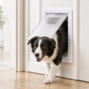 A black and white Border Collie dog is walking through a white pet door with a hinged flap, set in a clean indoor room with light wood flooring at Pet Servo