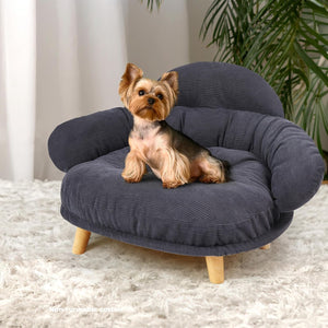Small dog sitting on a blue pet bed with wooden legs in a home setting at Pet Servo
