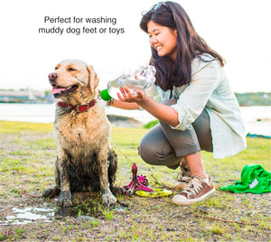 Woman washing a muddy dog with a bottle outdoors at Pet Servo