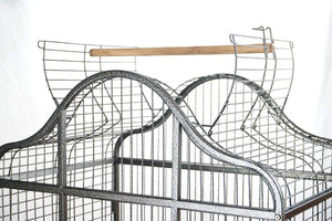 Close-up of a wire bird cage with a wooden perch on a white background at Pet Servo