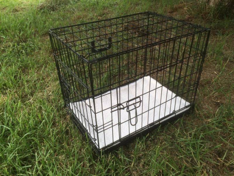 Black metal pet crate on grass at Pet Servo
