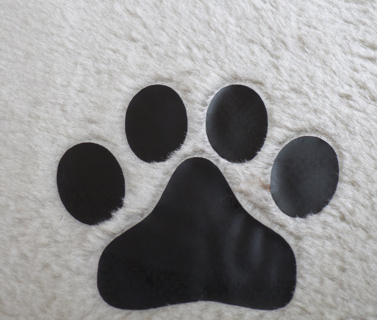 Black paw print on a textured white surface at Pet Servo