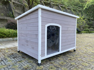 Wooden dog house with a glass door on a paved area with greenery in the background at Pet Servo