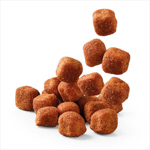 A pile of small, irregularly shaped brown coated pieces, some of which are floating above a main cluster, photographed on a clean white background.