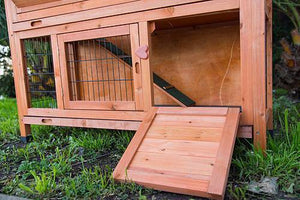 Wooden rabbit hutch with a open door on grass at Pet Servo