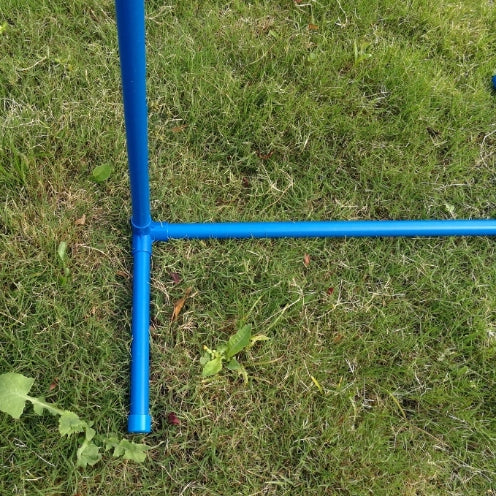 A bright blue metal frame component, likely a stand or rack, set up on a green grass lawn at Pet Servo