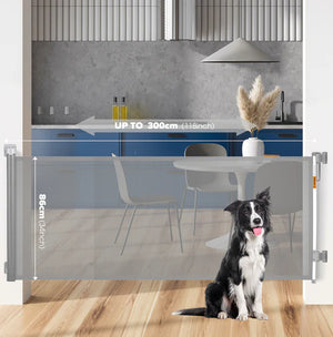 Dog standing behind a retractable pet gate in a kitchen.