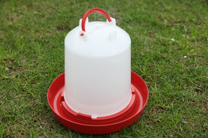 White plastic poultry drinker with red base on grass at Pet Servo