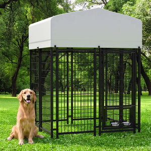 Dog sitting next to a large black dog crate with a white top in a park setting.