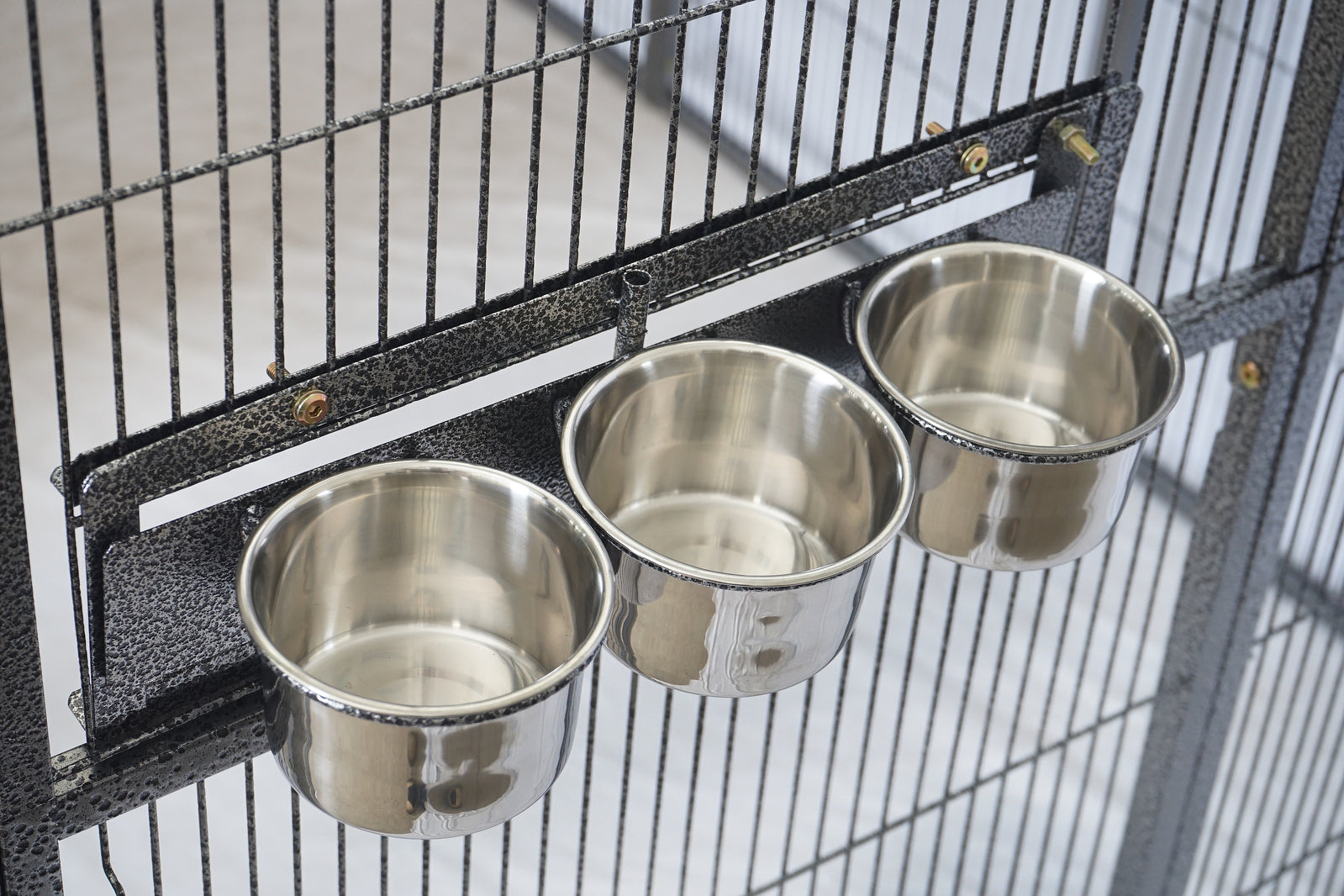Three metal bird feeders attached to a black birdcage at Pet Servo