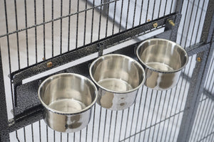 Three stainless steel pet bowls hanging from a black metal wire cage or feeder rack at Pet Servo