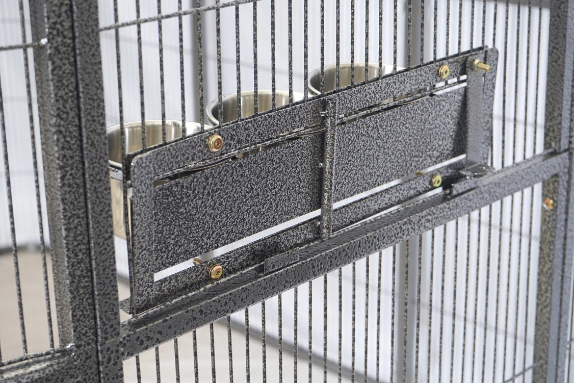 Close-up of a metal pet enclosure or cage with a textured dark gray panel and two stainless steel bowls mounted on the side at Pet Servo