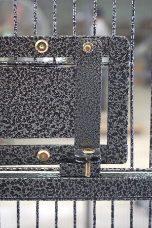 Close-up of a metal gate or enclosure with a black and gray speckled finish, featuring brass-colored mounting screws and a vertical latch bracket at Pet Servo