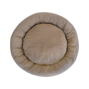 Round beige pet bed on a white background