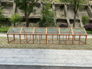 Wooden frame with glass panels in front of a concrete wall and trees at Pet Servo