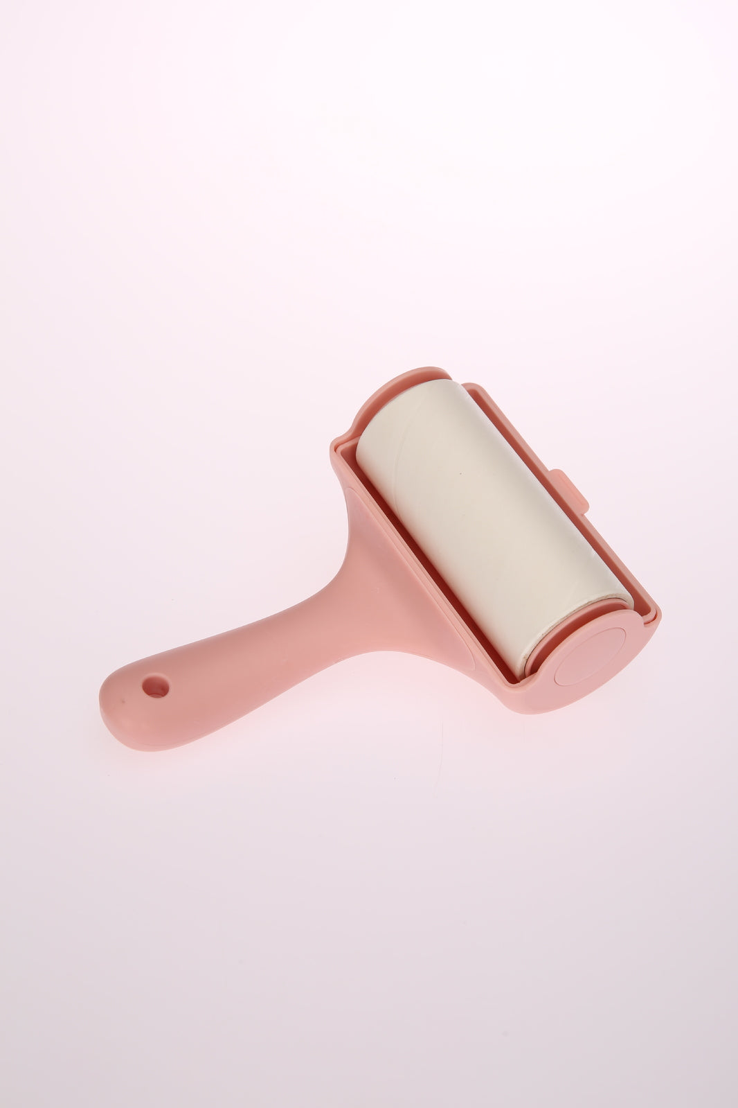 Pink pet hair remover with white roller on a light pink background at Pet Servo