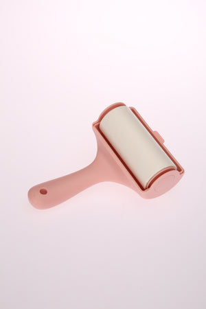 Pink pet hair remover with white roller on a light pink background at Pet Servo