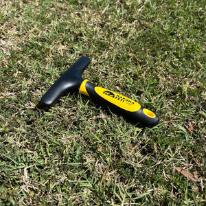 Pet grooming brush with black and yellow handle on grass