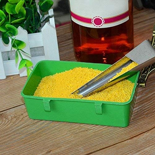 Green container with yellow beads and tongs on a wooden surface with a bottle in the background at Pet Servo