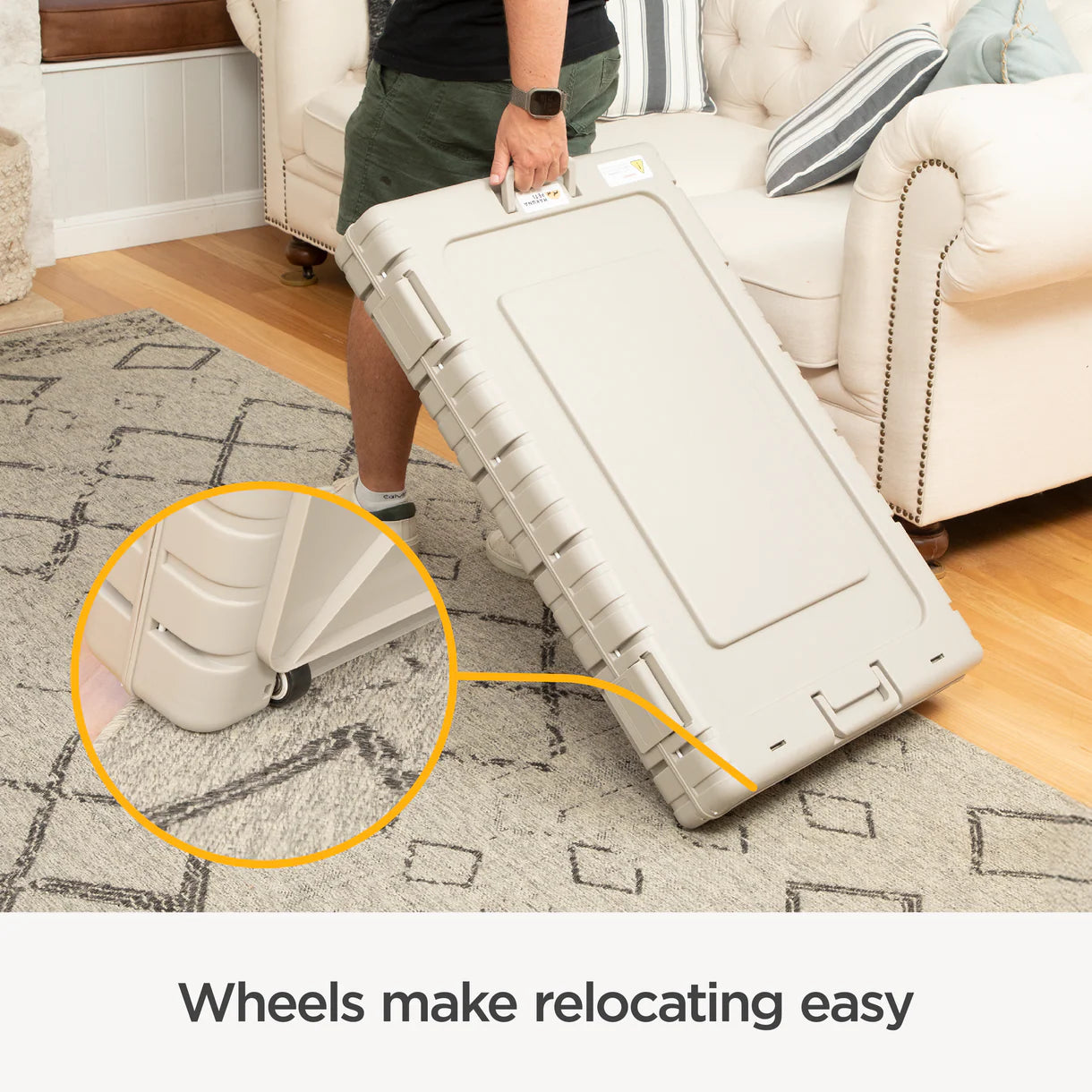 Person holding a large beige suitcase with wheels on a carpeted floor, emphasizing ease of movement.