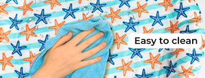 A hand wipes a light blue towel over a white fabric with blue and orange starfish patterns. A white text overlay reads 'Easy to clean' at Pet Servo