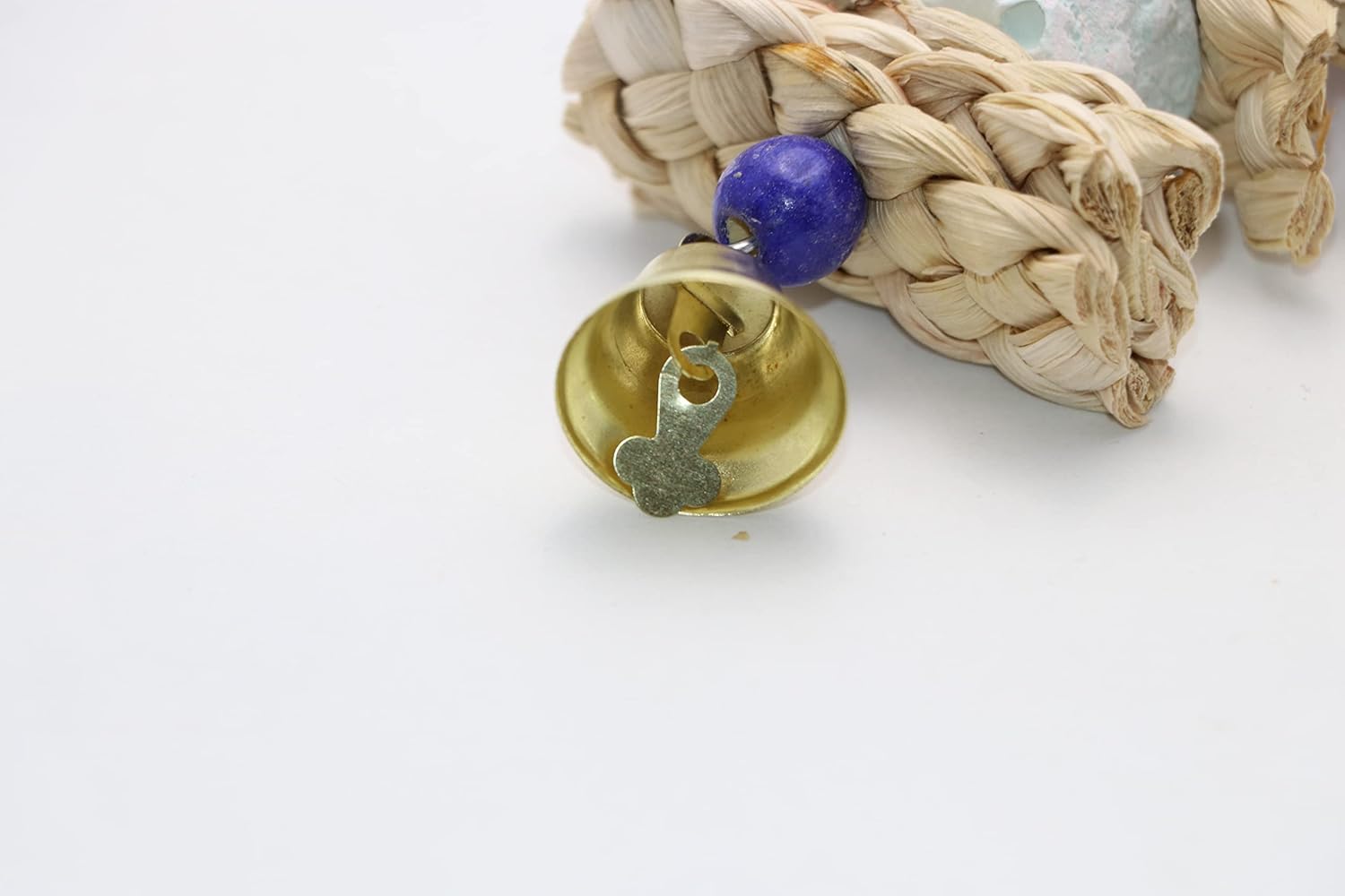 Gold bell with purple stone on a braided beige cord against a white background at Pet Servo