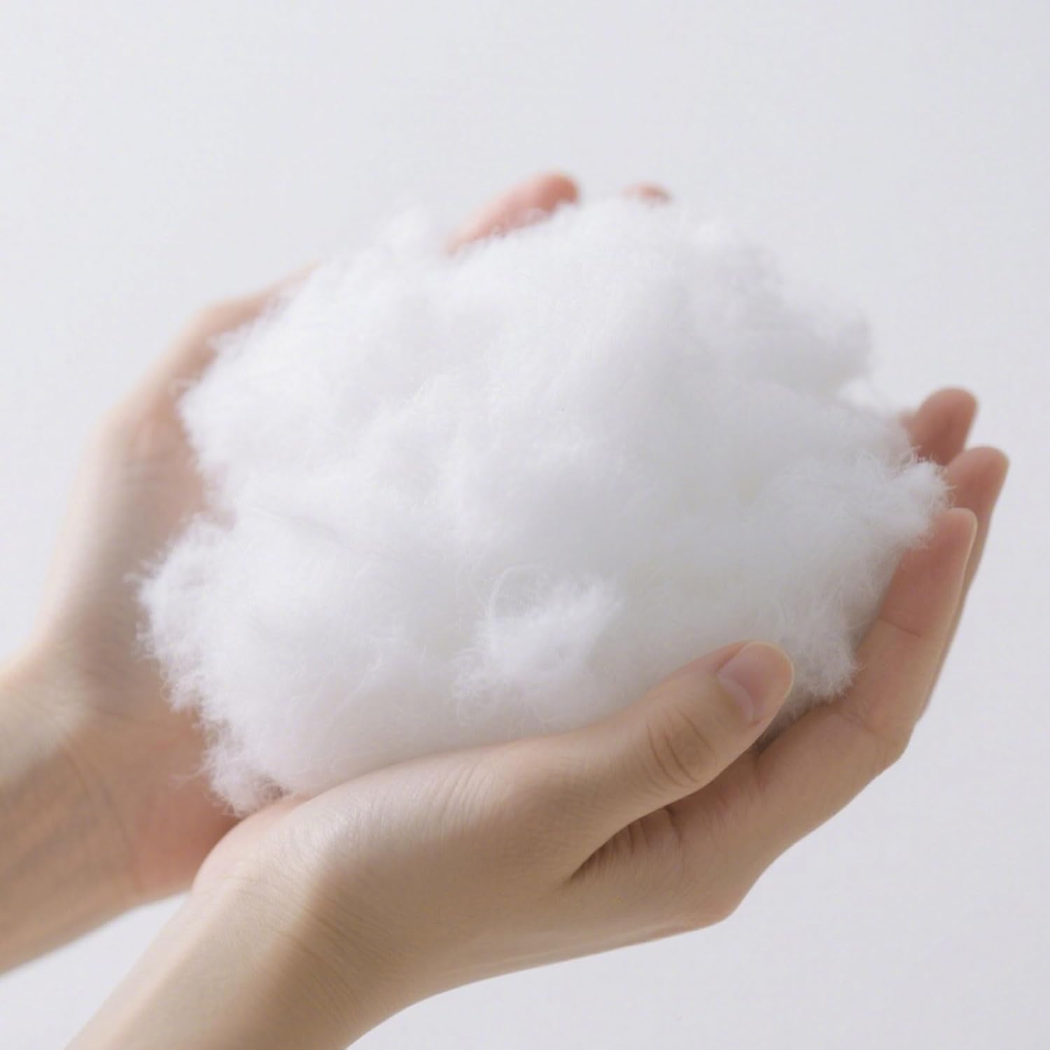 Hands holding a large ball of white cotton on a light gray background at Pet Servo